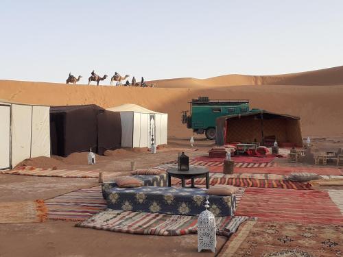 a desert with people riding on top of a sand dune at Camp atlantic chegaga in Mhamid