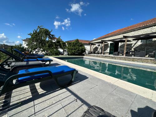 a row of lounge chairs next to a swimming pool at Quinta da Casa Cimeira, Guest House, Wines & Food in Valença do Douro