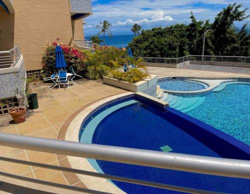 a large swimming pool next to a house with acean at Apartamento a la orilla de la playa en Pampatar, Isla de Margarita in Pampatar