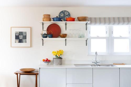 a kitchen with white cabinets and a sink and a window at Bowden Retreats in Dartmouth