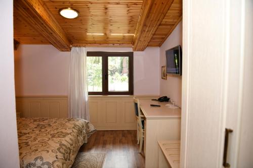 a bedroom with a bed and a desk and a window at Hotel Restaurant Dreri in Tirana