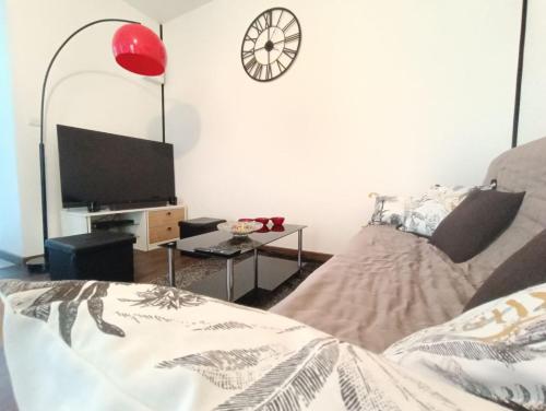 a living room with a bed and a clock on the wall at Escapade blésoise in Blois