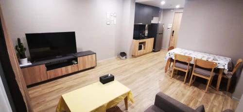 a living room with a television and a table and chairs at Blossom condo in Yan Nawa