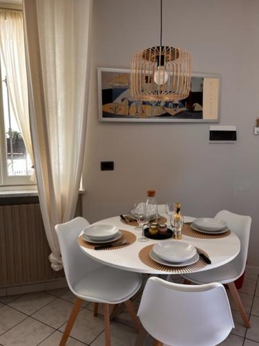 a dining room table with white chairs and a chandelier at Bon Bon del Viale-con posto auto privato in Asti