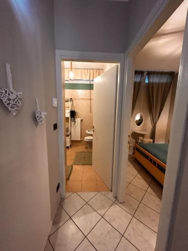 a hallway leading to a bathroom with a bed and a toilet at Bon Bon del Viale-con posto auto privato in Asti