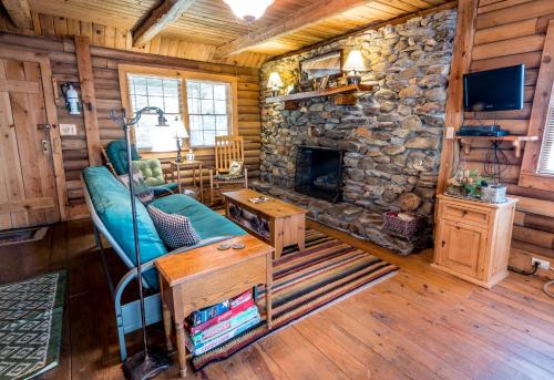 a living room with a couch and a stone fireplace at Creekside Hideaway Rustic Cabin - Secluded, Creekside Family Cabin in Topton