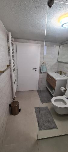 La salle de bains est pourvue de toilettes, d'un lavabo et d'une porte. dans l'établissement Apartman Stari Grad - Ostrožac na Uni - Bihać Cazin, à Ostrožac