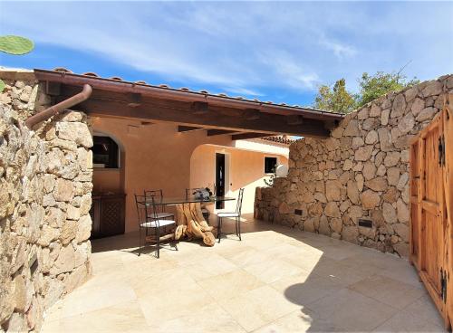 un patio con una mesa y una pared de piedra en Monica Luxury House, en Porto Cervo