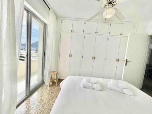a bedroom with a white bed with a large window at Apartamento primera línea Altea in Altea