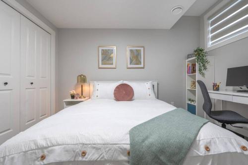 een witte slaapkamer met een groot bed en een bureau bij Your Perfect 2BR Stay in SE Calgary in Calgary