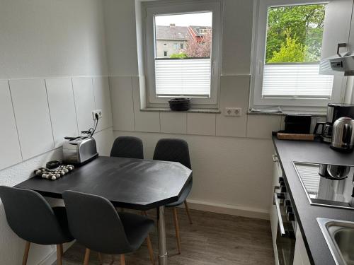 a kitchen with a table and chairs and two windows at Steinweg 7 Ferienwohnung in Kassel