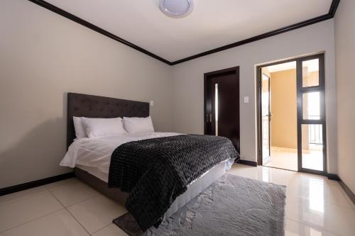 a bedroom with a bed with a black and white comforter at Fully furnished apartment. in Sandton