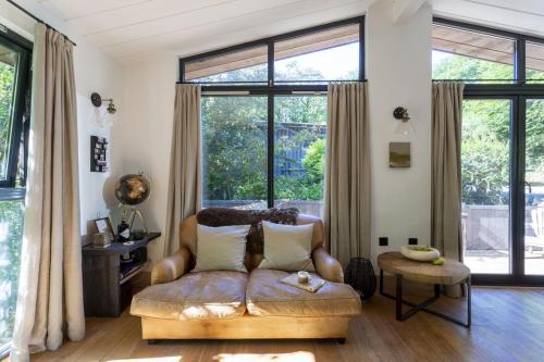 a living room with a couch and large windows at Den in the Woods in Slapton