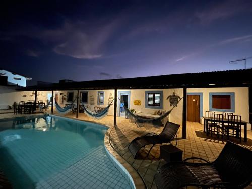 a pool with chairs and a hammock next to a house at Pousada Casa Feliz Maxaranguape in Maxaranguape