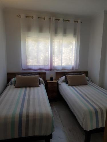 twee bedden in een kamer met een raam bij HR PARADISE CALA DE LA VILA JOIOSA in Cala de Finestrat