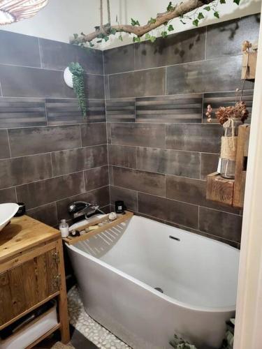 La salle de bains est pourvue d'une grande baignoire blanche à côté d'un lavabo. dans l'établissement Une invitation à la détente, à Nice