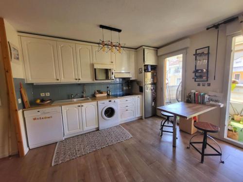 une cuisine avec des armoires blanches et une table à l'intérieur dans l'établissement Une invitation à la détente, à Nice