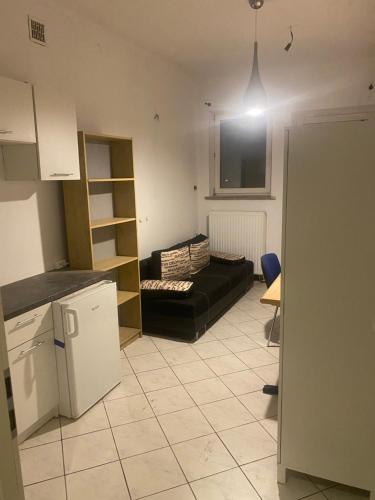 a kitchen and a living room with a black couch at Fałata apartament in Kobyłka