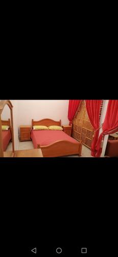 a bedroom with a bed and red curtains at Younes résidence 3 in Asilah