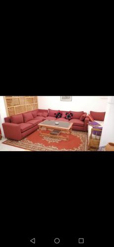 a living room with a red couch and a table at Younes résidence 3 in Asilah