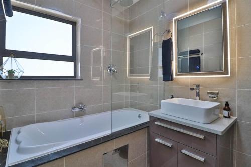 a bathroom with a tub and a sink and a window at Fully furnished apartment. in Sandton