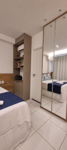 1 dormitorio con cama y espejo en Mana Beach Resort Muro Alto Prime - Luxo e conforto em Porto de Galinhas en Porto de Galinhas