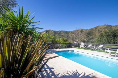 a swimming pool with mountains in the background at Cabañas Noscohue in Villa General Belgrano