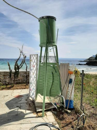 a green chair sitting next to the ocean at House Kokkalas on the beach in Pyrgadikia