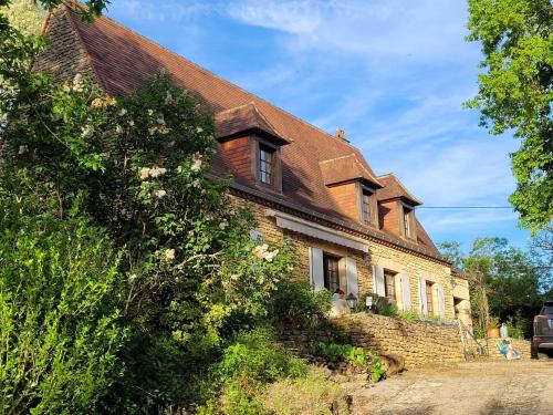 une ancienne maison en briques avec un toit brun dans l'établissement Villa met zwembad Dordogne, à Limeuil