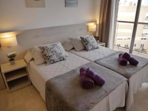 Dos camas en una habitación con toallas púrpuras. en Marina Beach Apartaments en Lloret de Mar