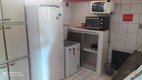 uma pequena cozinha com frigorífico e micro-ondas em Flats quase beira mar ar piscinas estac caseiro em Itamaracá