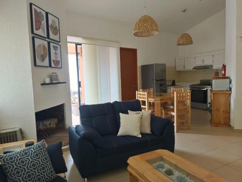 a living room with a blue couch and a kitchen at GoBaja Villas 2 bedroom in La Paz