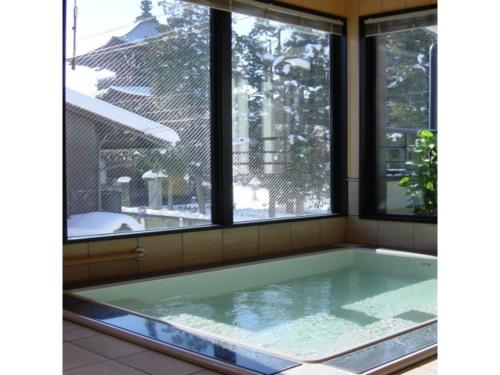 uma banheira de hidromassagem num quarto com janelas em Minshuku Kuwataniya - Vacation STAY 96480v em Takayama