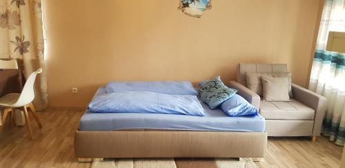 ein Bett mit blauer Bettwäsche und ein Sofa in einem Zimmer in der Unterkunft Ferienwohnung in dem schönen Kurort Bad Dürkheim in Bad Dürkheim