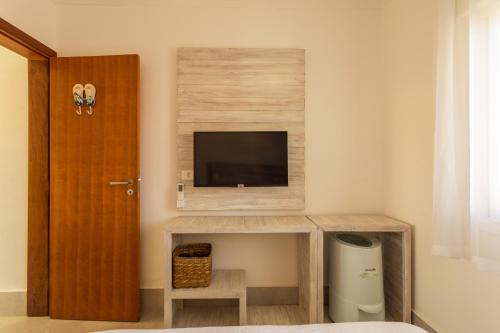 a small room with a tv and a bed at Casa d'Aroeira Residencial Boutique - Centro de Juqueí - 2 quadras do mar - Serviço de Praia - Roupa de Cama 600 fios algodão Egípcio - Toalhas Banho e Praia - Tudo Novo - Estacionamento Interno - Cozinha - Consulte unidades com Ofurô Hidro e Cromoterapia in Juquei