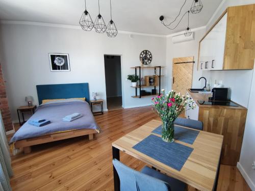 Un dormitorio con una cama y una mesa con flores. en Apartamenty w ścisłym centrum Kupiecka-Drzewna, en Zielona Góra