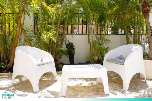 2 weiße Stühle und ein Tisch vor Bäumen in der Unterkunft Private Pool, With Access to Beach Club, VSandra, 2BR in Punta Cana