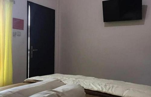 メラウケにあるKost Haji Nainiのベッド1台、壁掛けテレビが備わる客室です。