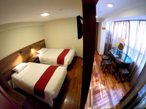 a hotel room with two beds and a desk and a desk at Zans Apartments Cusco in Cusco