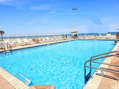 a large blue swimming pool with chairs and acean gmaxwell at Oceanfront Escape With Balcony and heated salt water pool! in Daytona Beach