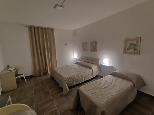 a hotel room with two beds and a desk at Casa Castelli in Messina