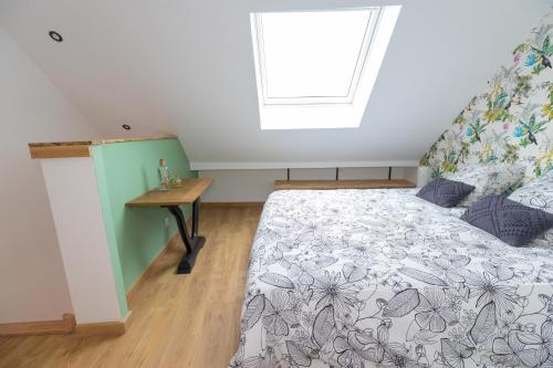 a bedroom with a bed and a table and a window at Le paille en queue in Sainte-Mère-Église