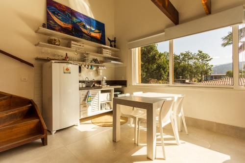 a kitchen with a table and a refrigerator at Casa d'Aroeira Residencial Boutique - Centro de Juqueí - 2 quadras do mar - Serviço de Praia - Roupa de Cama 600 fios algodão Egípcio - Toalhas Banho e Praia - Tudo Novo - Estacionamento Interno - Cozinha - Consulte unidades com Ofurô Hidro e Cromoterapia in Juquei