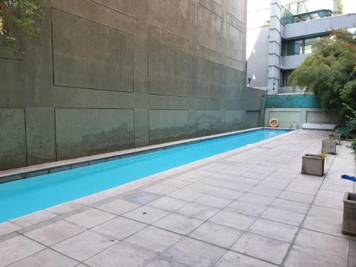 a swimming pool next to a building at Departamento con excelente ubicación cerca metro los Leones in Santiago