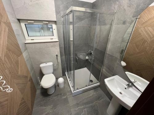 a bathroom with a shower and a toilet and a sink at Domek Przy Plaży in Gąski