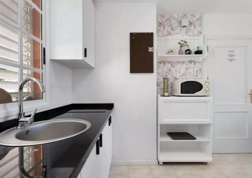 cocina blanca con fregadero y microondas en Apartamento El Carmen 3 Lara, en Santa Cruz de Tenerife