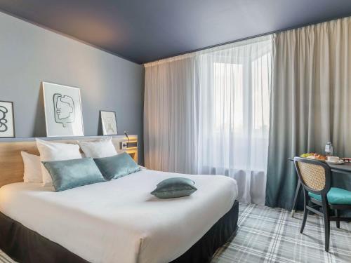 維萊豐坦的住宿－Mercure Lyon Est Villefontaine，酒店客房设有一张大床和一张书桌。