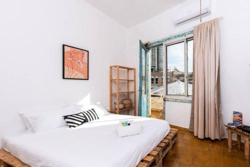 a bedroom with a large white bed and a window at Close in Tel Aviv