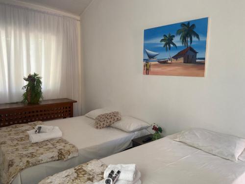 ブジオスにあるPousada Maresias de Geribáのベッド2台が備わる部屋、壁に絵が飾られた部屋