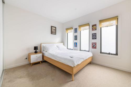 1 dormitorio blanco con 1 cama y 2 ventanas en 3BR Point Cook Holiday Sanctuary, en Point Cook
